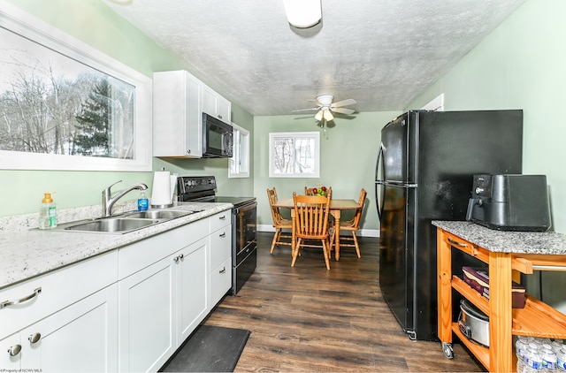 kitchen featuring a textured ceiling, a sink, white cabinets, dark wood-style floors, and black appliances