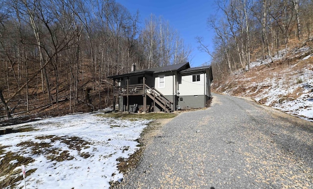 view of front facade with gravel driveway, crawl space, stairway, and a deck