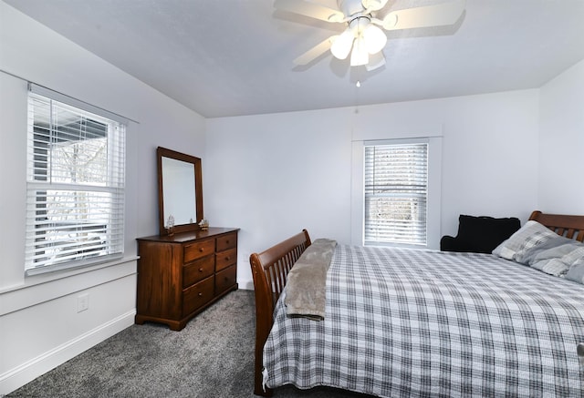 bedroom featuring multiple windows, baseboards, dark colored carpet, and a ceiling fan