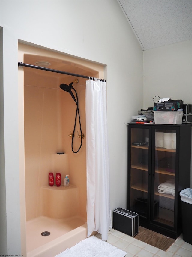 full bath featuring vaulted ceiling, a stall shower, tile patterned flooring, and a textured ceiling