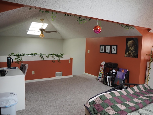 bedroom with visible vents, lofted ceiling with skylight, a ceiling fan, carpet flooring, and a textured ceiling