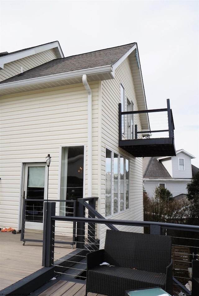 exterior space with roof with shingles and a balcony