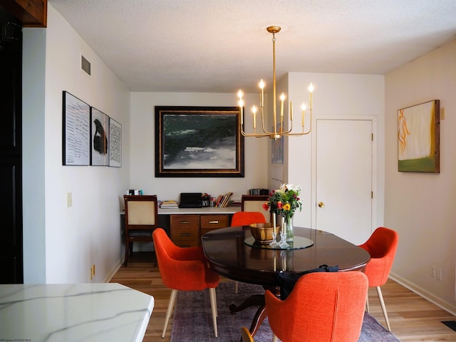 dining space with baseboards, an inviting chandelier, visible vents, and light wood-style floors