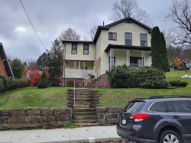 traditional-style house with a porch, stairway, and a front lawn