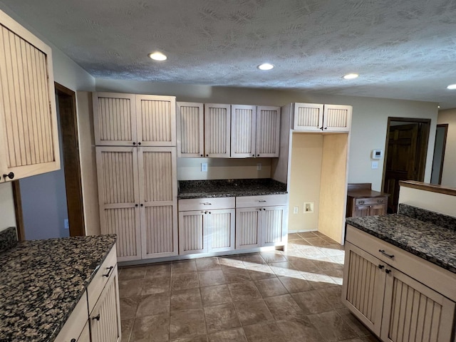 kitchen featuring a textured ceiling, dark stone countertops, and recessed lighting