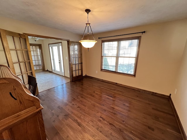 unfurnished dining area with dark wood finished floors and baseboards