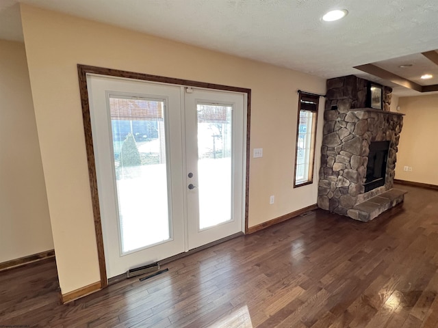 entryway featuring french doors, baseboards, a stone fireplace, and dark wood-style flooring