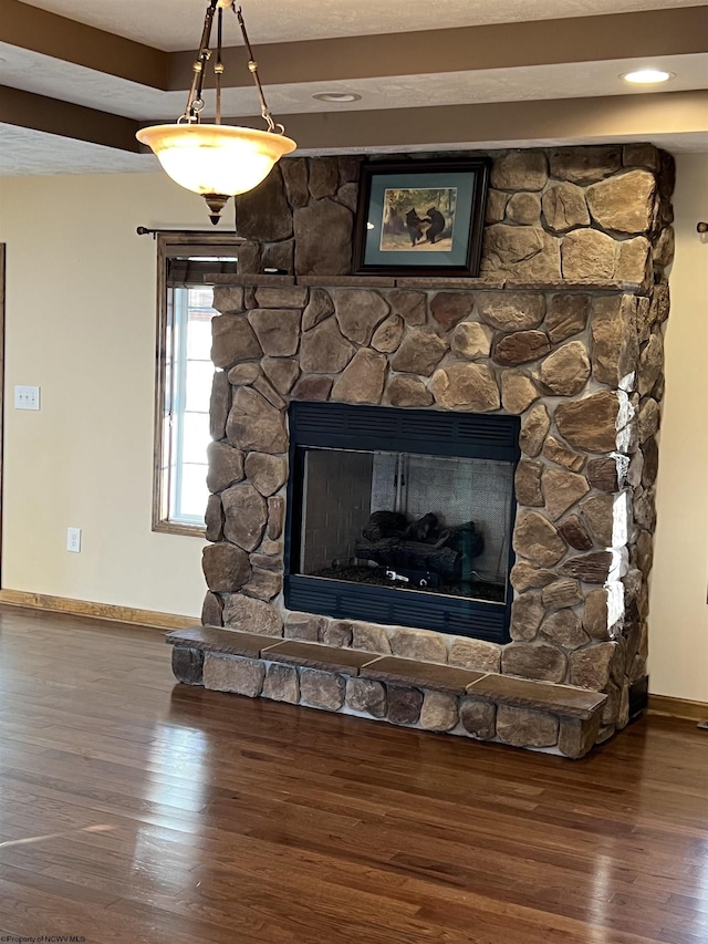 details featuring a stone fireplace, wood finished floors, and baseboards