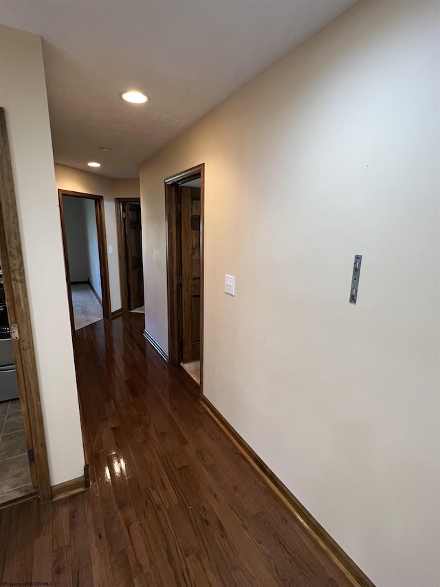 corridor featuring baseboards, dark wood-type flooring, and recessed lighting