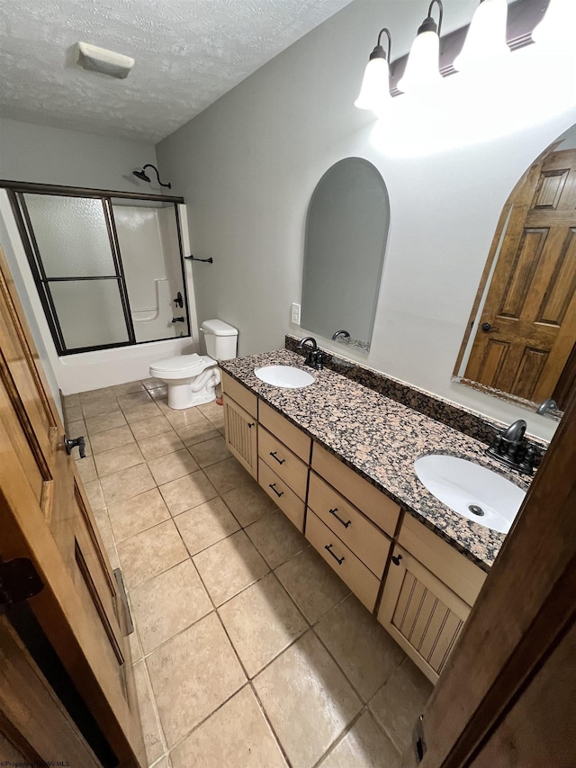 bathroom with double vanity, bath / shower combo with glass door, a sink, and toilet