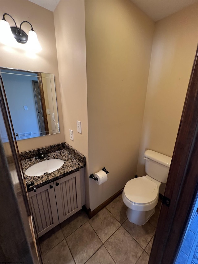 bathroom featuring baseboards, vanity, toilet, and tile patterned floors