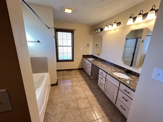 bathroom featuring double vanity, a bath, tile patterned floors, a textured ceiling, and a sink