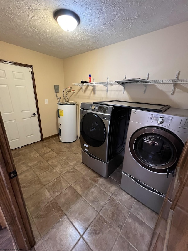 washroom featuring water heater, laundry area, a textured ceiling, and washing machine and dryer