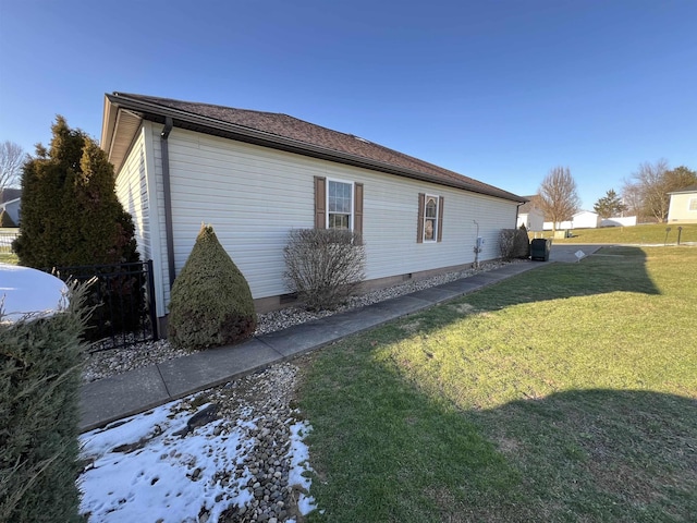 view of side of home featuring crawl space, fence, and a lawn