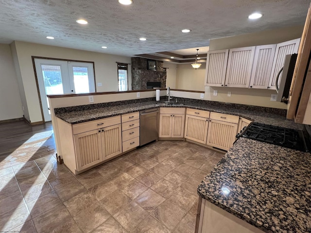 kitchen with a textured ceiling, a peninsula, a sink, appliances with stainless steel finishes, and pendant lighting