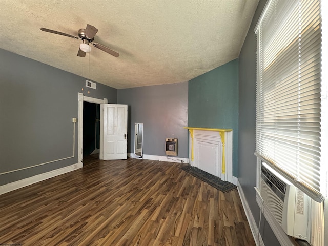 unfurnished living room with baseboards, dark wood-style floors, ceiling fan, heating unit, and a textured ceiling