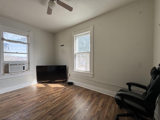 unfurnished room featuring a textured ceiling, cooling unit, dark wood-style flooring, a ceiling fan, and baseboards