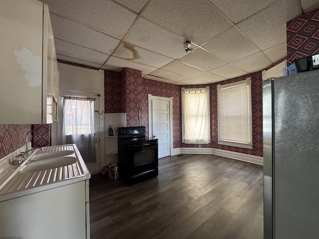 kitchen featuring wallpapered walls, dark wood-style flooring, freestanding refrigerator, black range with electric cooktop, and a sink