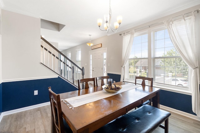 dining room with light wood-style floors, a notable chandelier, stairway, and a wealth of natural light