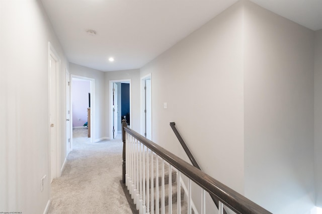 corridor featuring baseboards, light colored carpet, and an upstairs landing