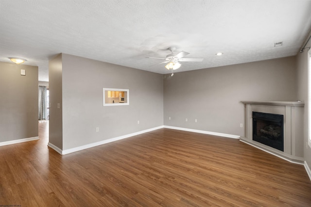 unfurnished living room featuring dark wood-style floors, ceiling fan, a fireplace, and baseboards