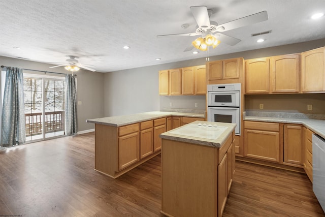 kitchen with light countertops, visible vents, light brown cabinets, a kitchen island, and white appliances