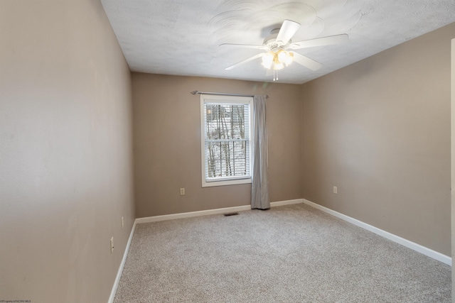 empty room featuring baseboards, visible vents, a ceiling fan, light colored carpet, and a textured ceiling