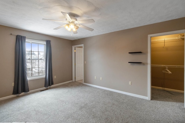 empty room featuring ceiling fan, a textured ceiling, carpet, and baseboards