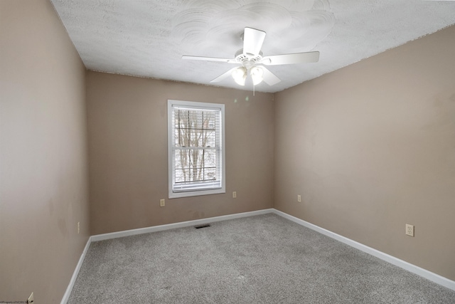 carpeted empty room with a ceiling fan, visible vents, a textured ceiling, and baseboards