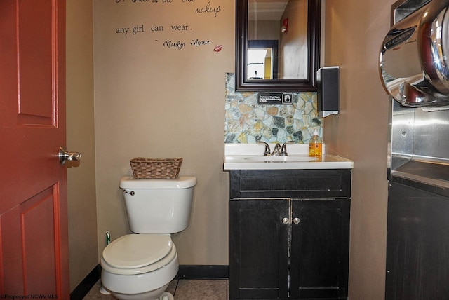 half bath featuring tile patterned flooring, toilet, vanity, baseboards, and decorative backsplash