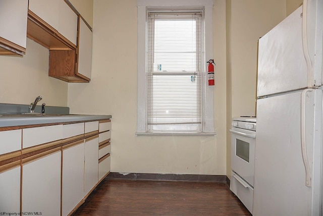 kitchen featuring a sink, white appliances, white cabinetry, and dark wood-type flooring