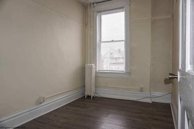 unfurnished room featuring radiator and dark wood-style flooring