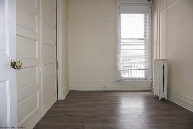 unfurnished room with radiator heating unit and dark wood finished floors