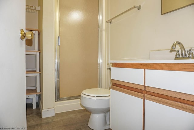 bathroom featuring toilet, a stall shower, wood finished floors, and vanity