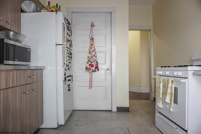 kitchen featuring light countertops, white appliances, brown cabinetry, and baseboards