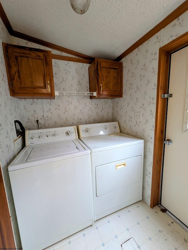 laundry area featuring wallpapered walls, cabinet space, a textured ceiling, washer and dryer, and light floors