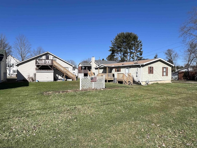 rear view of house with stairs, a deck, and a lawn