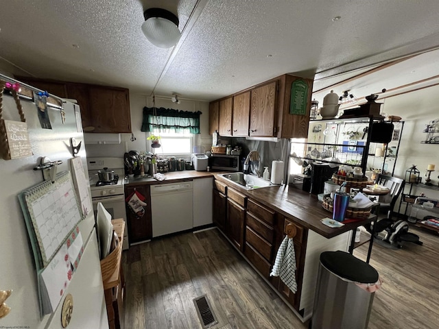 kitchen featuring white appliances, visible vents, dark wood-style flooring, and a sink