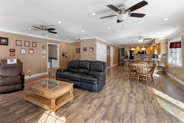 living room featuring baseboards, recessed lighting, wood finished floors, and crown molding