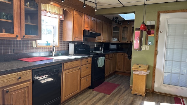 kitchen featuring glass insert cabinets, dark countertops, under cabinet range hood, and black appliances