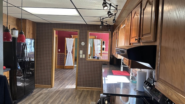 kitchen featuring a paneled ceiling, dark wood-style flooring, dark countertops, and black fridge