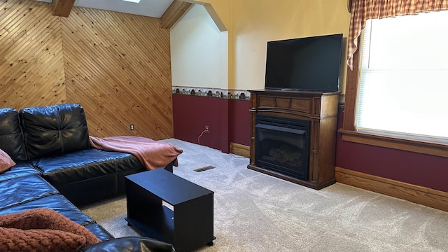 living area with wooden walls, visible vents, light colored carpet, lofted ceiling with beams, and a fireplace