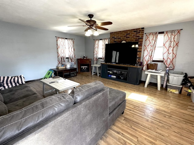 living area with a fireplace, wood finished floors, a ceiling fan, and baseboards