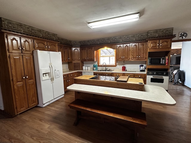 kitchen with dark wood-type flooring, a sink, light countertops, a center island, and black appliances