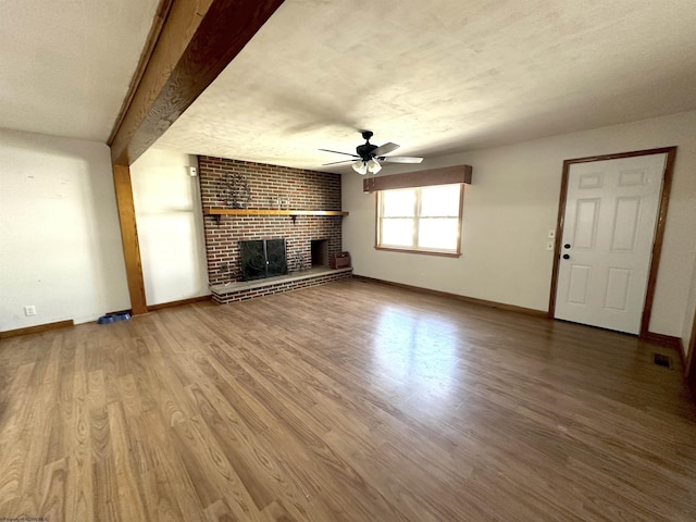 unfurnished living room featuring a brick fireplace, baseboards, a ceiling fan, and wood finished floors