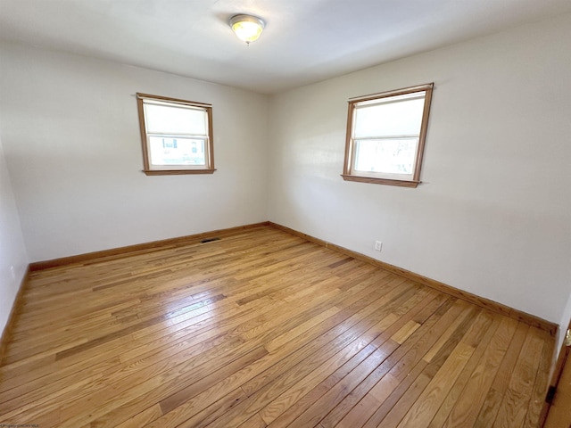 empty room with baseboards, a healthy amount of sunlight, and light wood-style floors