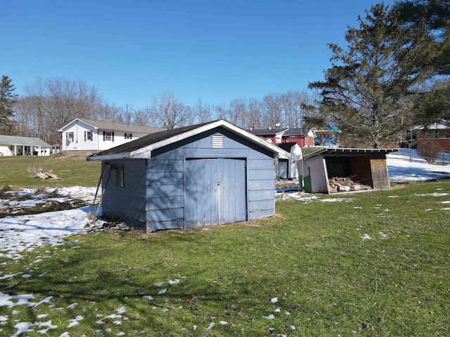 snow covered structure with an outdoor structure, a storage unit, and a lawn