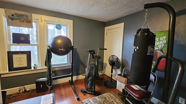 workout area with a wealth of natural light, a textured ceiling, baseboards, and dark wood-style flooring