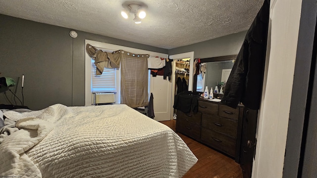 bedroom featuring dark wood finished floors, a walk in closet, cooling unit, a textured ceiling, and a closet