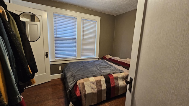 bedroom with dark wood finished floors, a textured ceiling, and baseboards